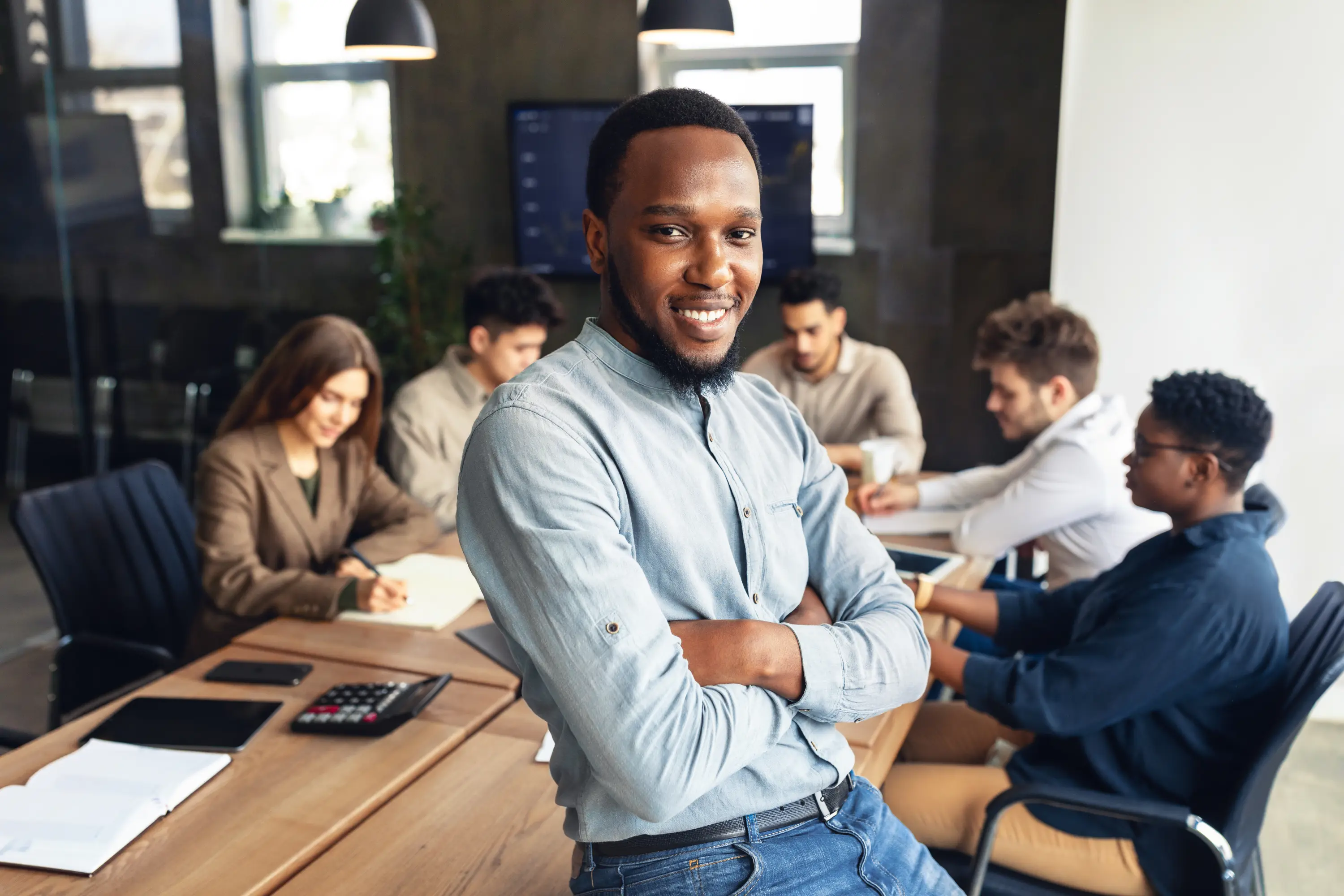A young professional in the office with his team behind him