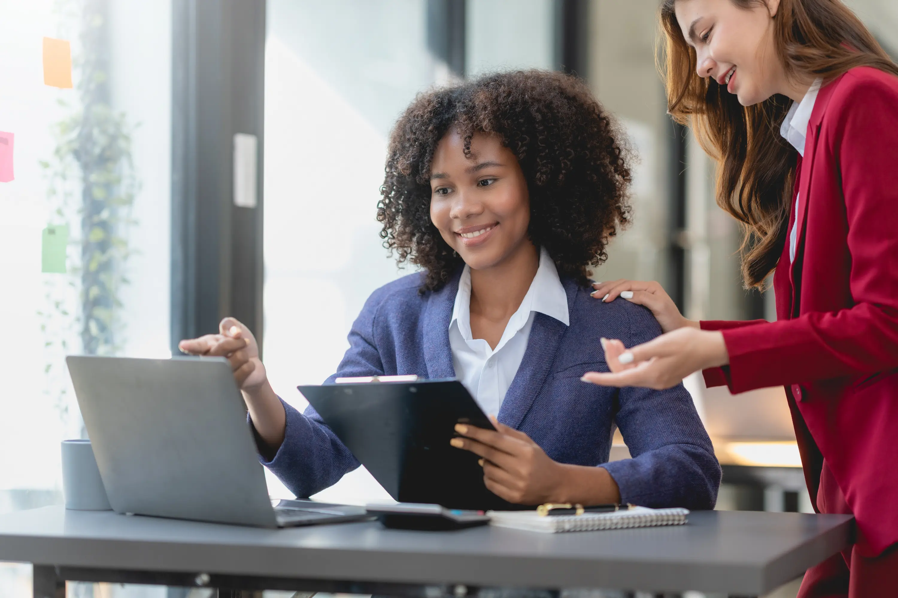 A manager guiding a young colleague at her desk